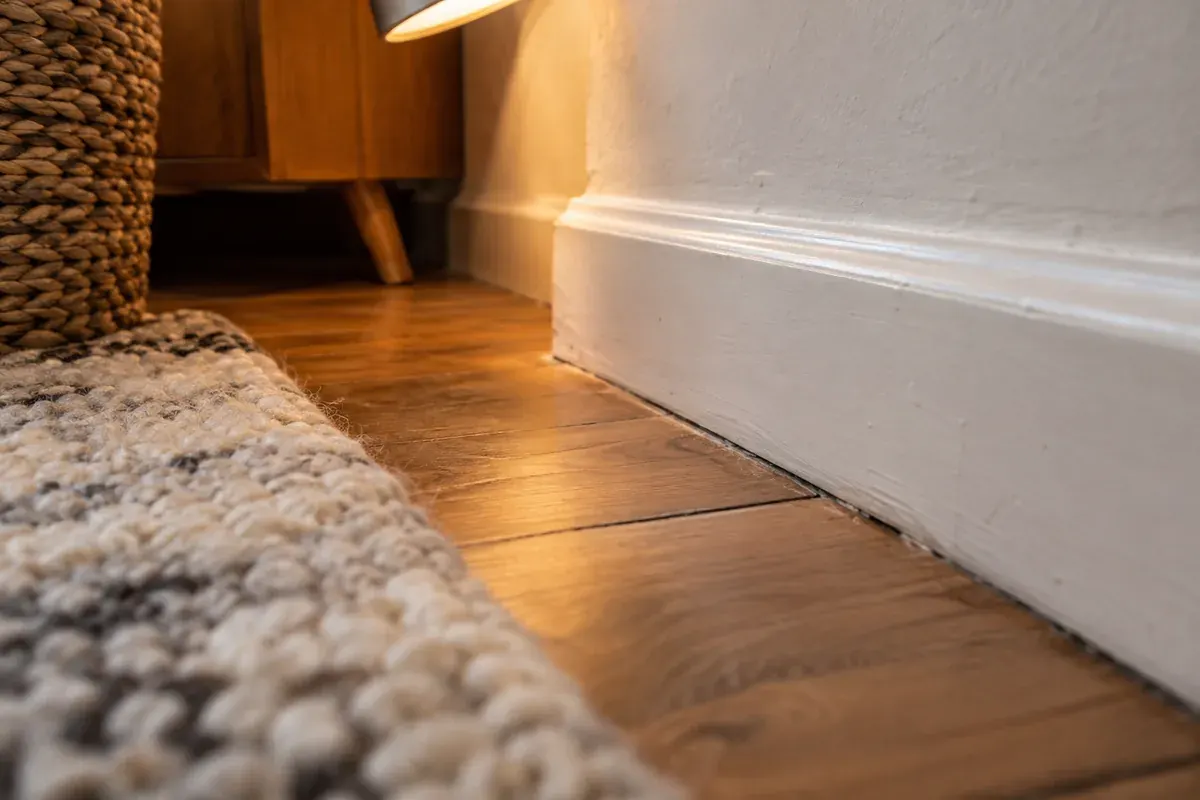Examiner les zones discrètes Angle entre une plinthe, un parquet et le bord d’un tapis.